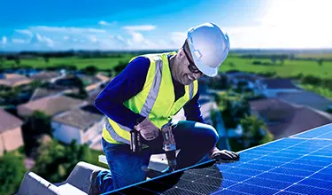 Homem sorrindo enquanto trabalha em placa solar.