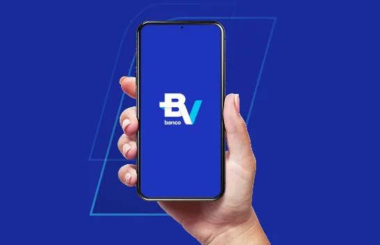 Mão segura um smartphone com a tela de abertura do aplicativo, que mostra o logo do banco BV.