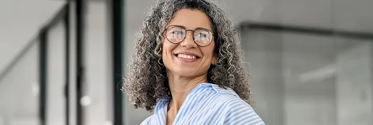 Mulher sorridente em frente a fachada de prédio.