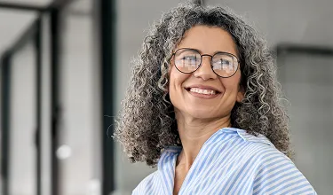 Mulher sorridente em frente a fachada de prédio.