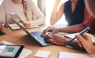 Pessoas reunidas sentadas a mesa em ambiente de trabalho.