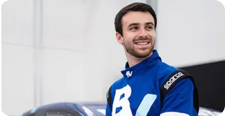 Um homem com roupa de piloto de corrida, encostado em um carro com a logo do banco BV.