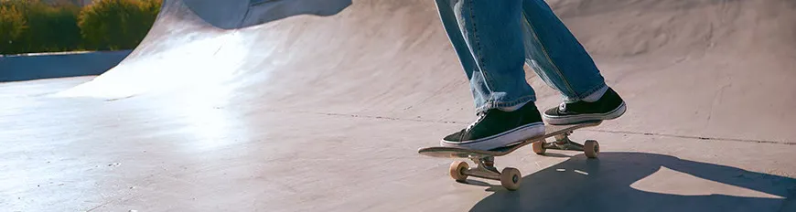 Uma pessoa de calça, andando de skate em uma pista.