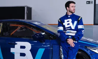 Felipe Baptista, promessa da Stock Car, com roupa de piloto patrocinado pelo banco BV, encostado em um carro.
