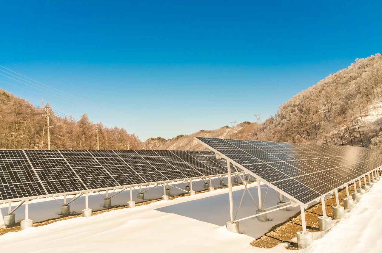 Vários painéis solares instalados no chão de uma região árida e com bastante incidência solar direta.