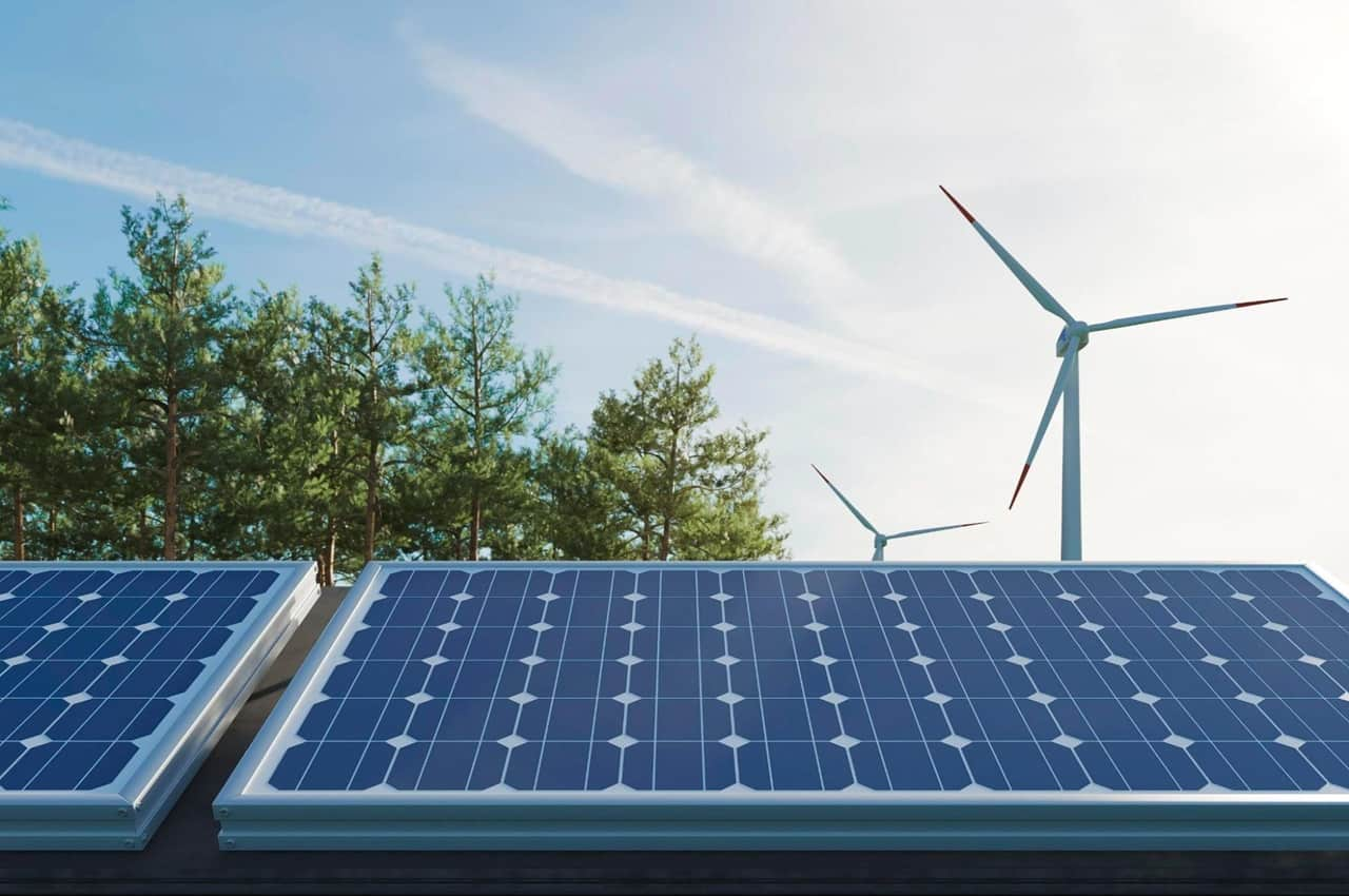 Fonte de energia limpa instalada. São duas placas de energia solar fotovoltaica instalada em telhado e, ao fundo do imóvel, tem duas hélices de energia eólica.