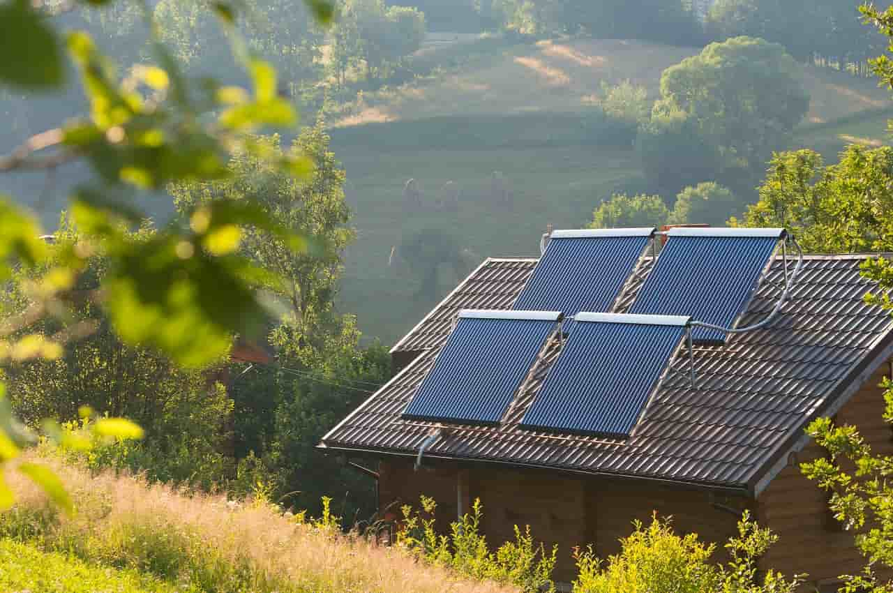 Residência em ambiente rural com quatro painéis solares instalados no telhado.