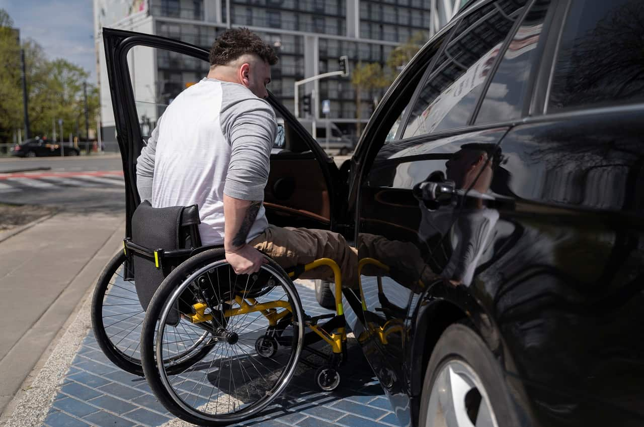 A imagem mostra uma pessoa com deficiência entrando em seu carro.