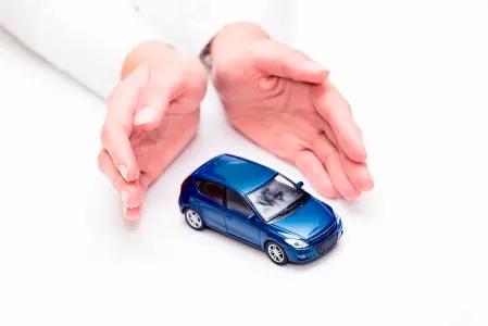 Mãos segurando pequeno carro azul de brinquedo, com detalhes realistas, sobre fundo branco.