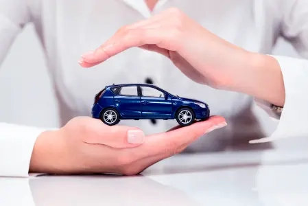 A imagem mostra uma pessoa de camisa branca segurando a miniatura um carro azul.