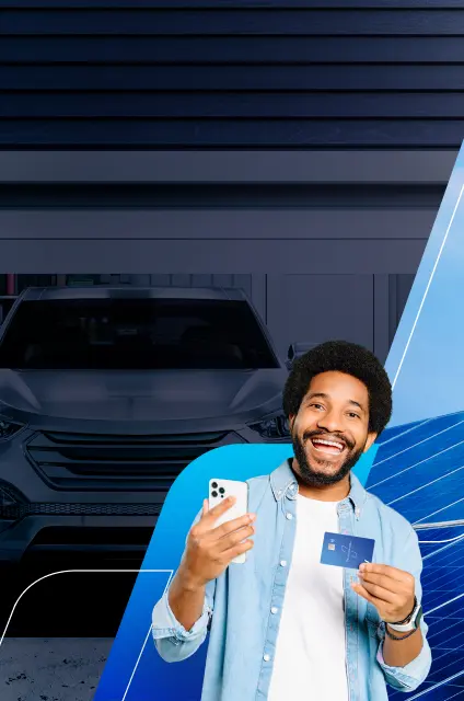 Imagem de um homem negro sorrindo, de camiseta azul e jaqueta jeans, segurando um celular e o cartão do banco, ao fundo temos a imagem de um carro cinza e placas solares