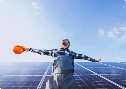 Homem em um painel solar, com braços abertos e capacete na mão