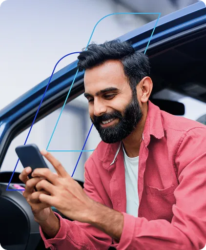 Homem de camisa vermelha sentado dentro do carro utilizando o celular