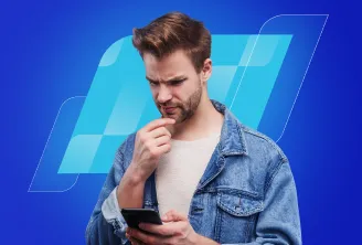 Um homem branco, de barba por fazer, olha pensativo para o celular.