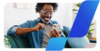 Um homem negro, de barba grisalha e óculos, olha feliz para o celular.