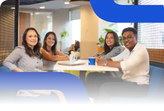 Um homem e três mulheres sorridentes, sentados ao redor de uma mesa em um ambiente corporativo.