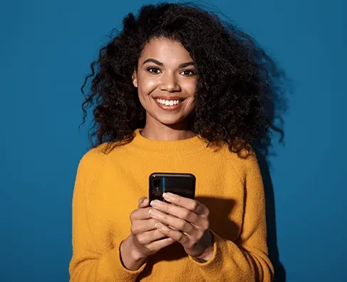 Mulher sorrindo, olhando para frente e segurando um celular