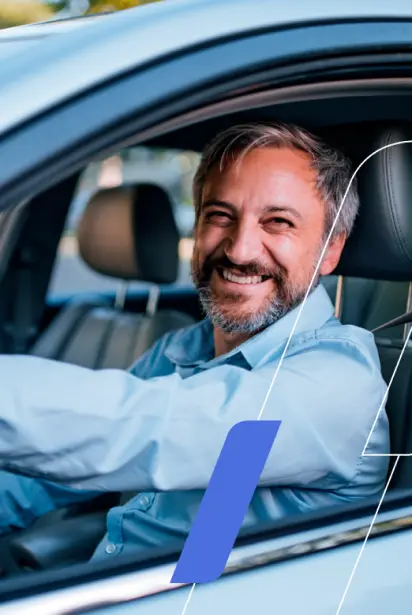 Na imagem há um homem dirigindo um carro sorrindo.