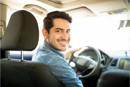 Na imagem podemos ver um homem sorrindo enquanto dirige o carro