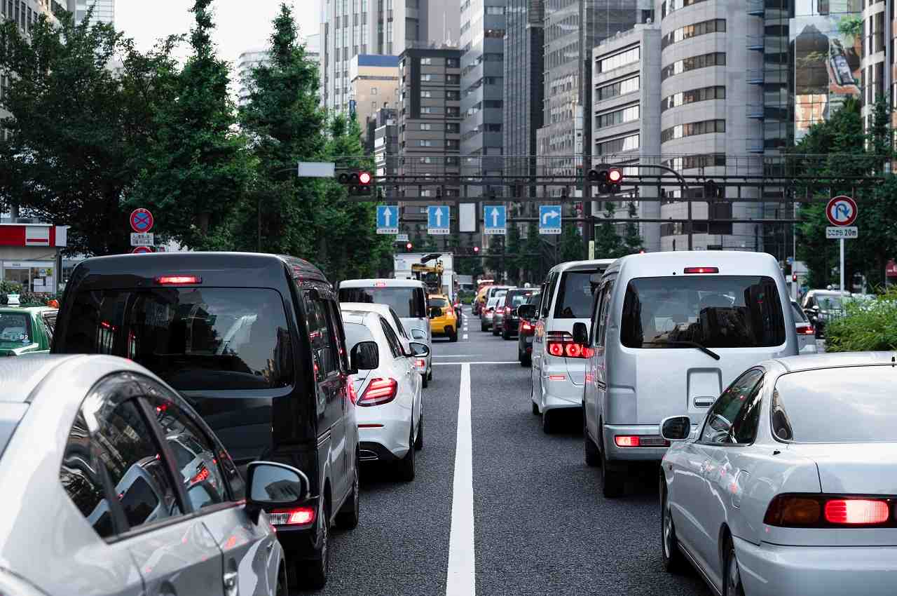 Fila de veículos estacionados no sinal vermelho e com congestionamento de carros ao redor.