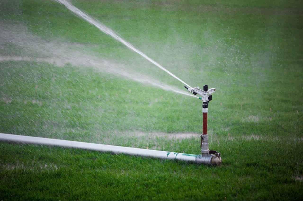 Irrigador ligando molhando um gramado com água.