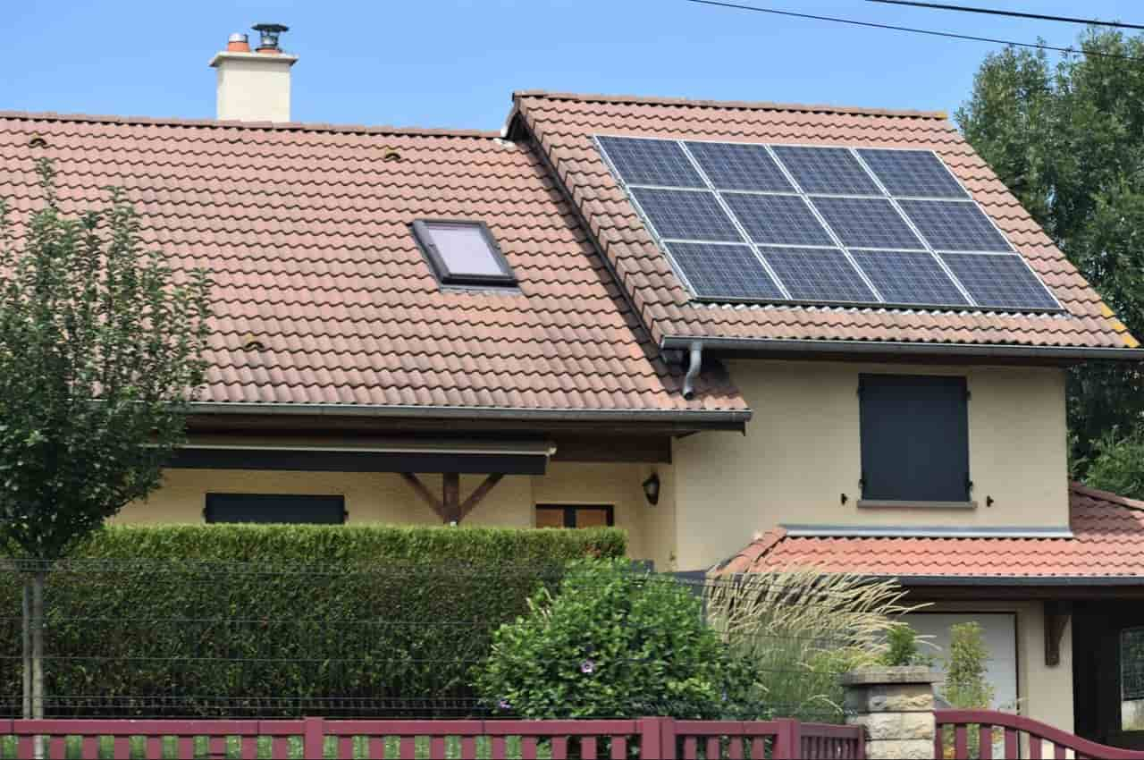 Casa com energia solar residencial instalada. A imagem mostra um telhado com placas solares instaladas e um céu azul límpido.