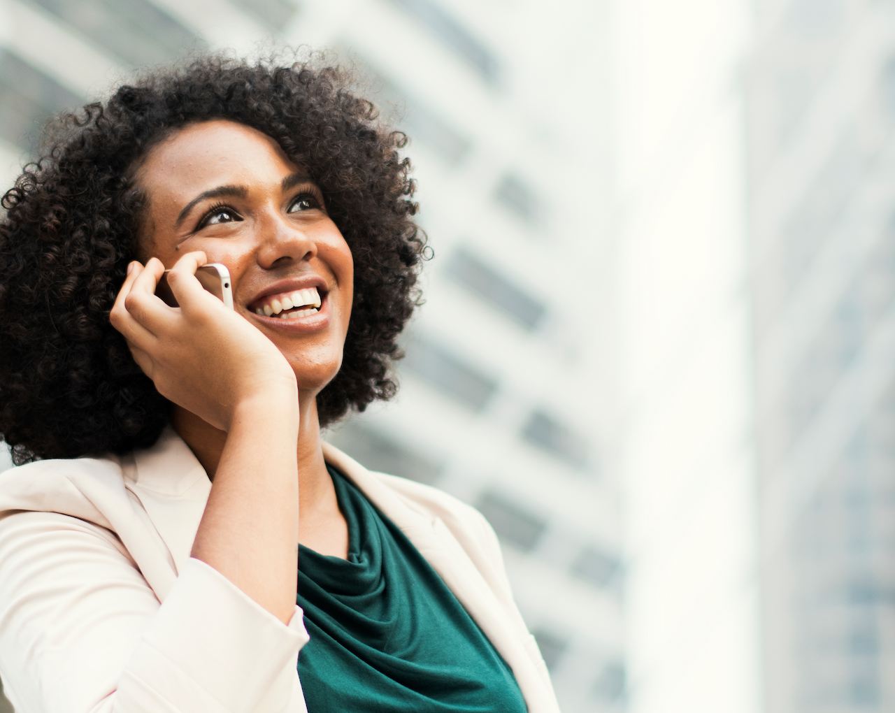 A imagem mostra uma mulher sorridente falando ao telefone.