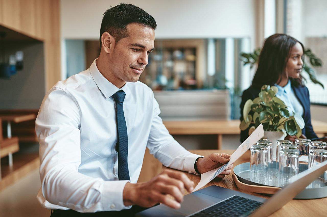 A imagem mostra um homem trabalhando em um estabelecimento com seu laptop.