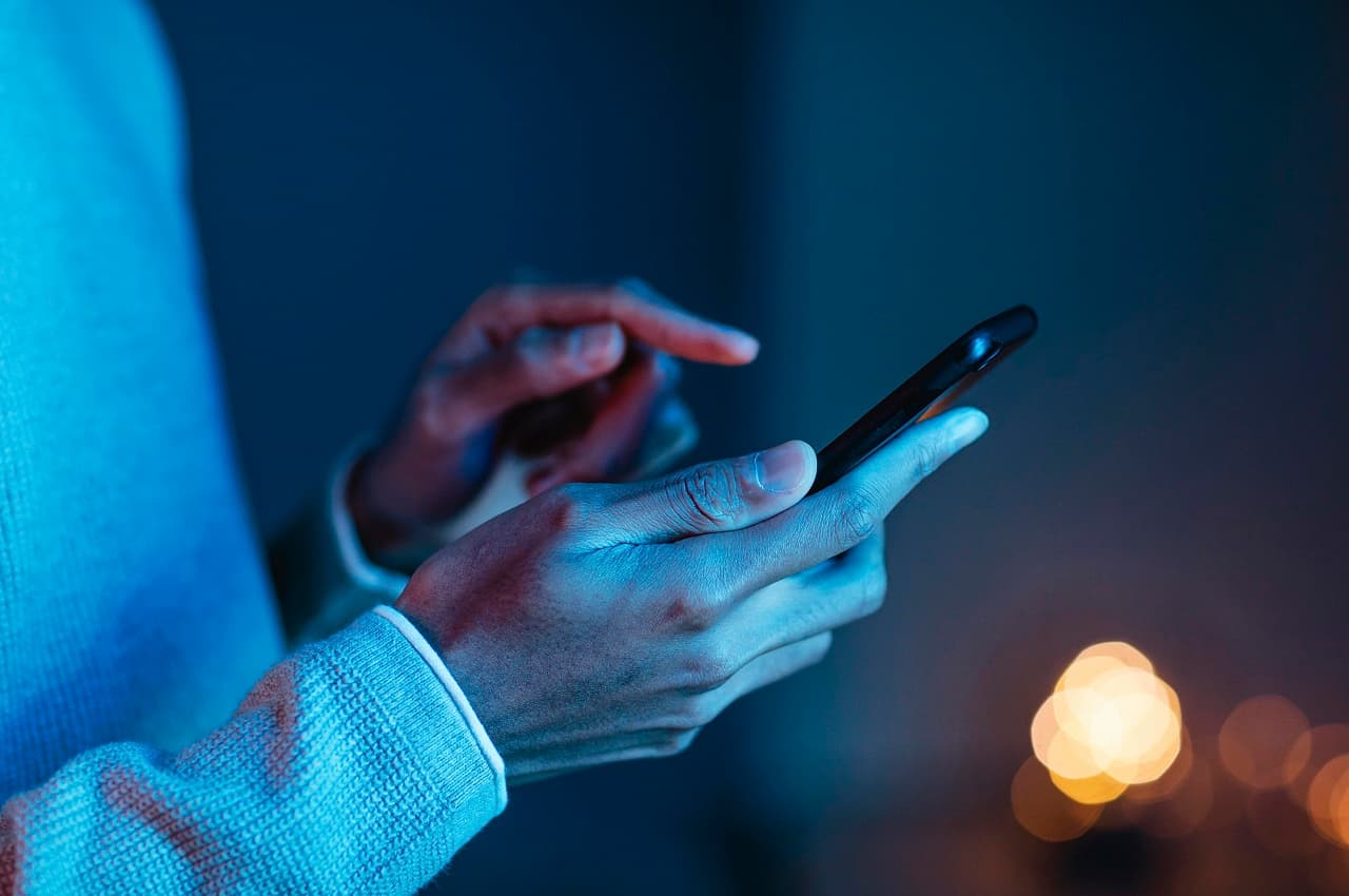 Homem utilizando celular e clicando na tela do aparelho com o dedo indicador.