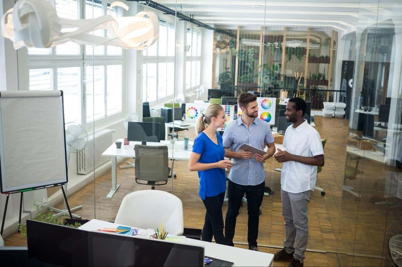 Grupo de três pessoas no escritório do trabalho conversando sobre como economizar energia na empresa.