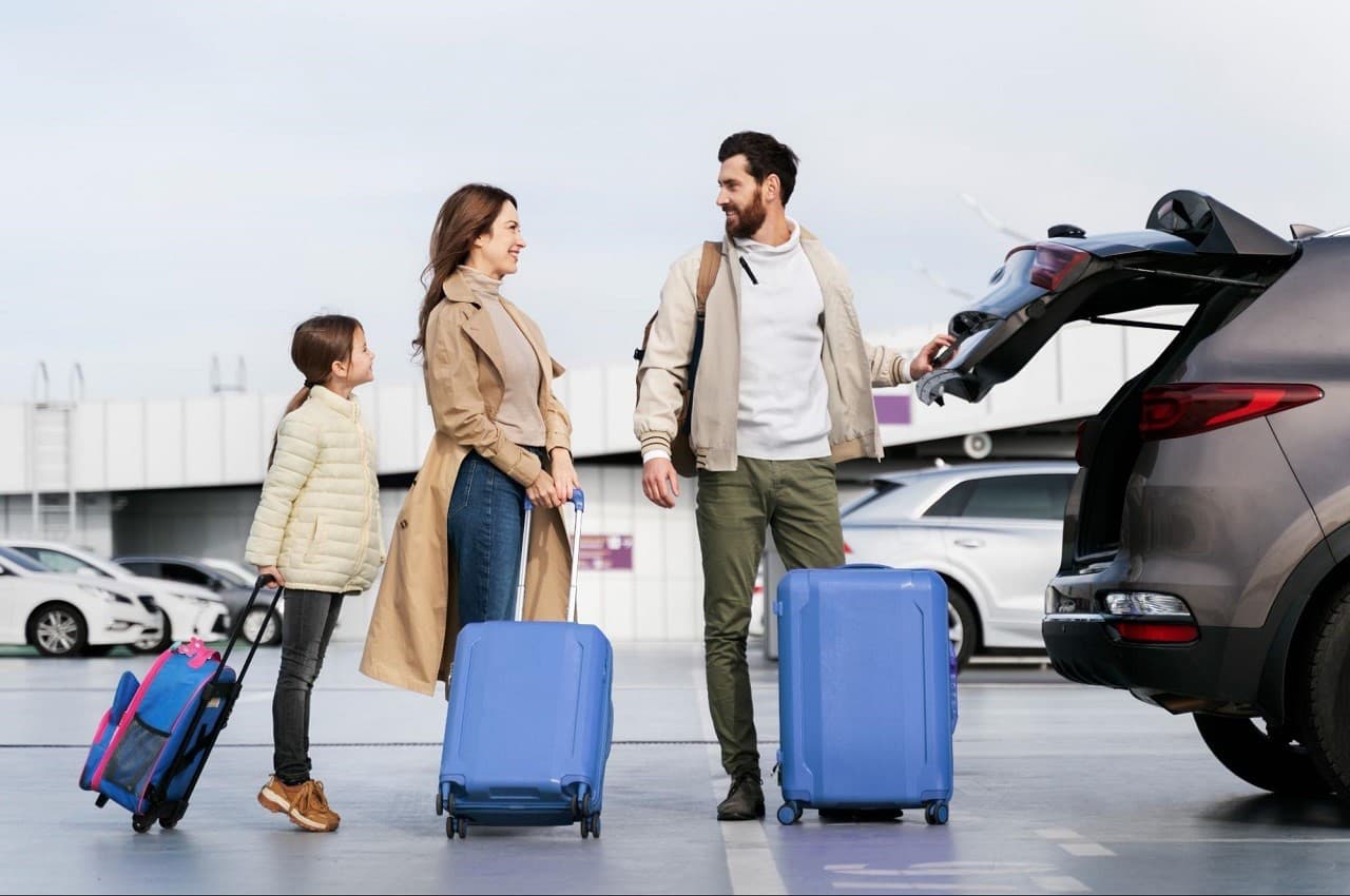 Família sorridente (mulher, homem e uma criança) viajando juntos e carregando malas azuis para um porta-malas. 