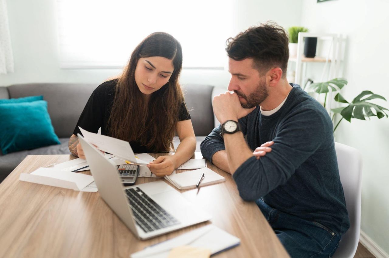 A imagem mostra um casal analisando as contas à pagar. 