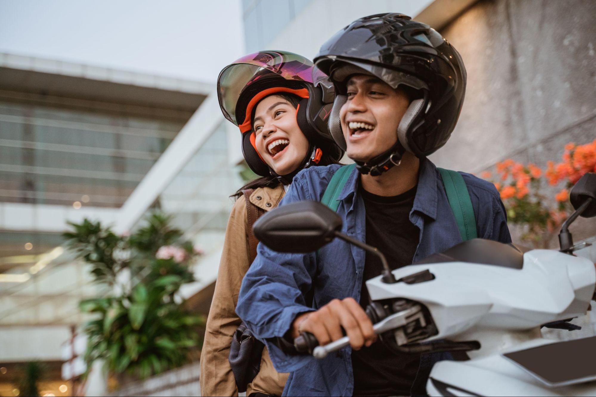 Casal sorridente andando em uma motocicleta branca.