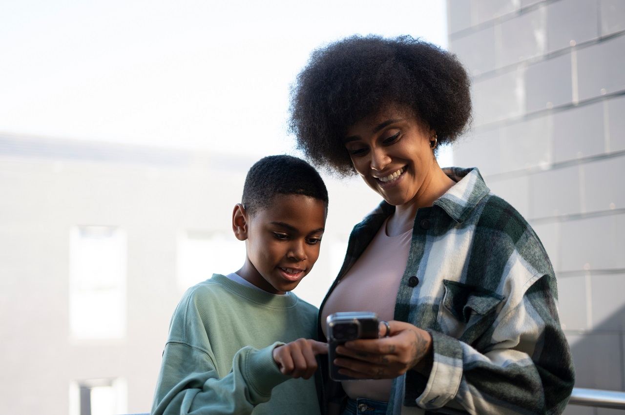 Criança apontando para a tela de celular de sua mãe.