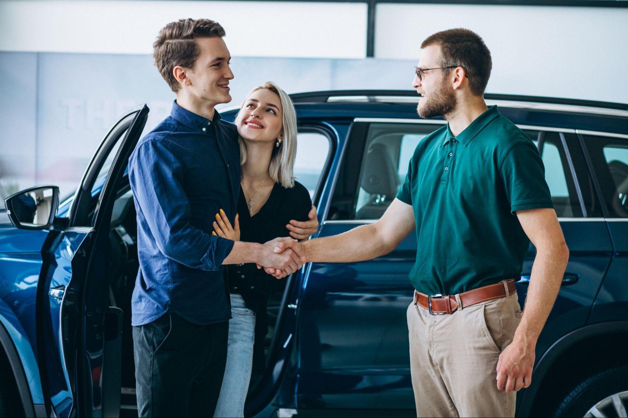 A imagem mostra um casal se abraçando, sorridentes, após adquirir um carro.