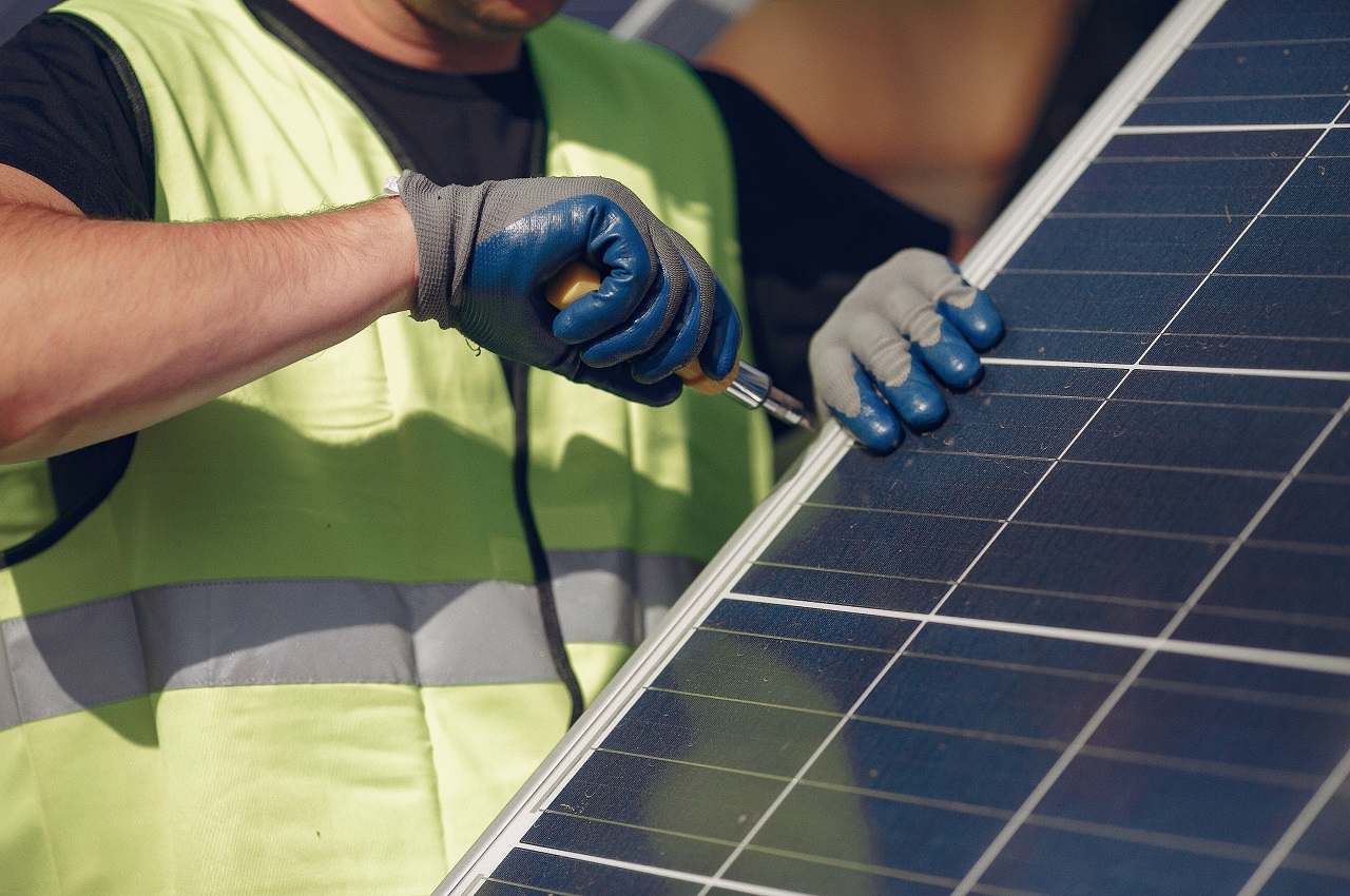 Foco em mão de um homem segurando chave de fenda para manutenção de placas solares.