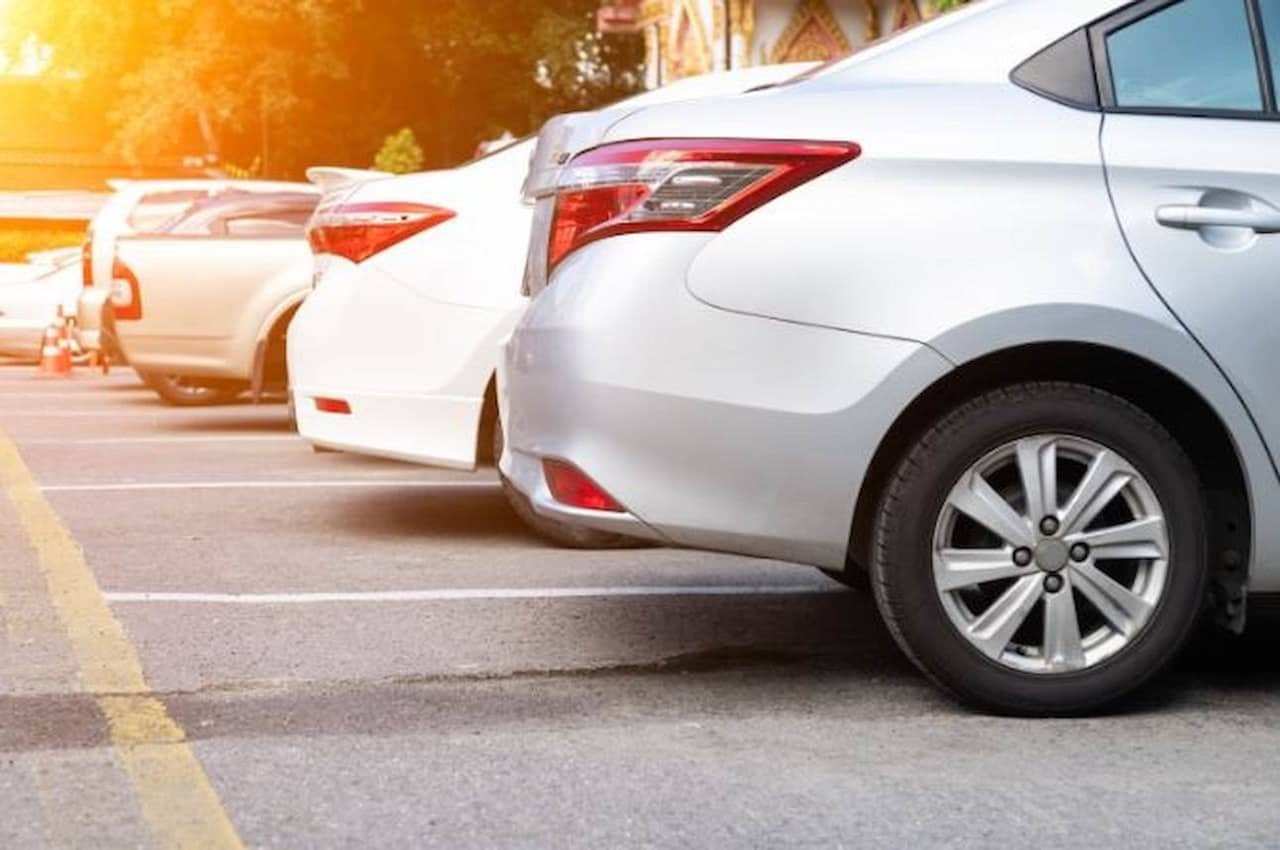 Veículos do modelo Sedan prata estacionados em lugar iluminado pela luz solar.