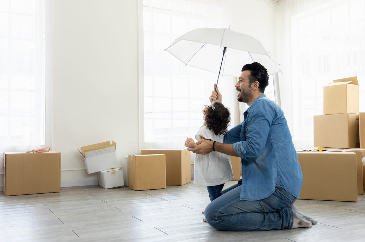 Homem com guarda-chuva transparente aberto dentro de casa e brincando com sua filha.