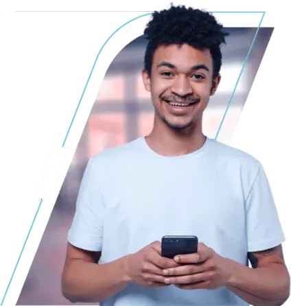 Na imagem vemos um homem de camisa branca, ele está segurando um celular e sorrindo.